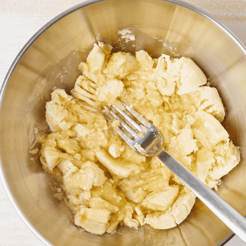 mashed bananas in a stainless steel bowl with a fork