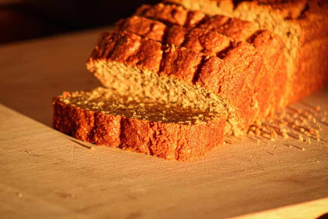 gluten free holiday pumpkin bread on a wooden cutting board with a few slices falling forward