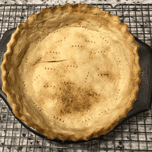 baked gluten and dairy free pie crust in a pie pan sitting on wire cooling rack