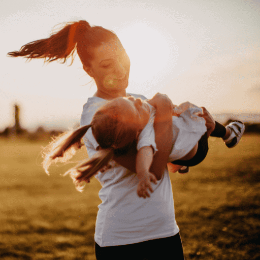 mother spinning around with her young daughter in her arms.