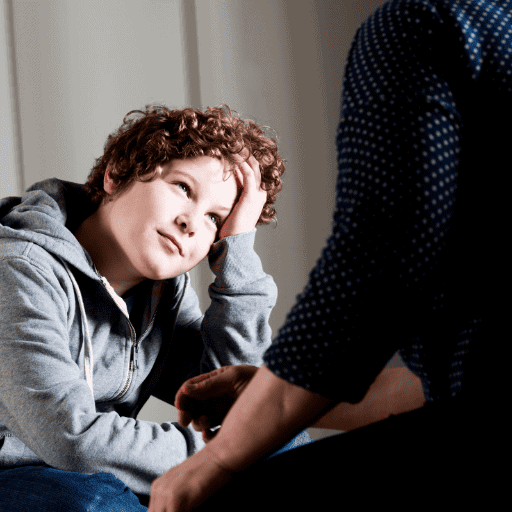 boy listening to woman in front of him. he is resting his hand on his head