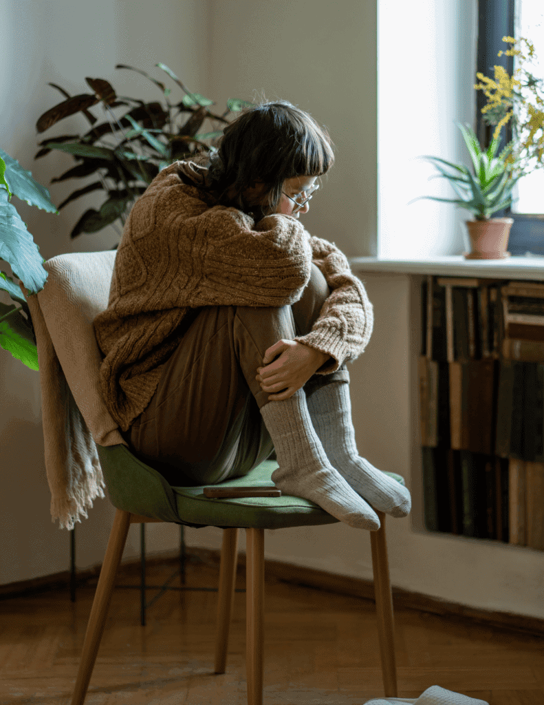 Teen girl sitting alone in a chair looking sad illustrating that hearing loss contributes to isolation and feelings of depression. 